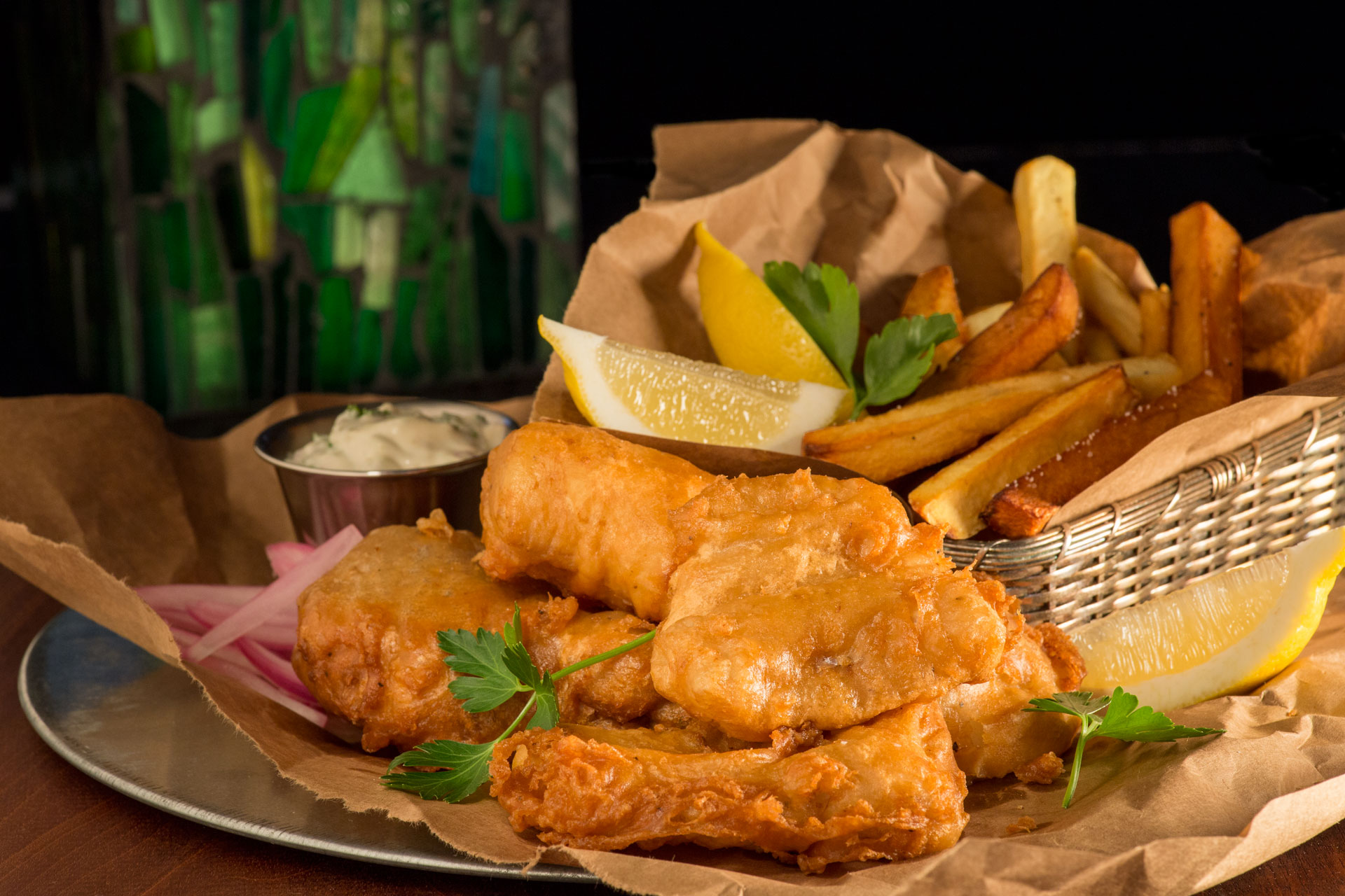 Unlike English fish and chips, which were traditionally served in folded newspaper, these light crispy beer battered fish and chips are served Irish pub-style piled on rustic torn brown paper bags with fresh-made tartar sauce, lemon, and malt vinegar.
