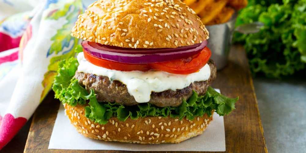 Photo depiction of a burger made with Australian lamb, Greek yogurt, lettuce, tomato and onion.