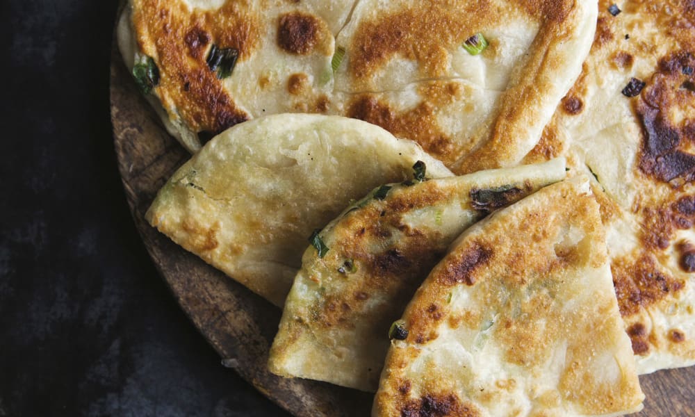 Unlike Western pancakes, Green Onion Pancakes, or Cong�you bing, are made with dough instead of batter. They are a savory flatbread that is folded with minced scallions and oil, and once you have one, you'll be craving another.