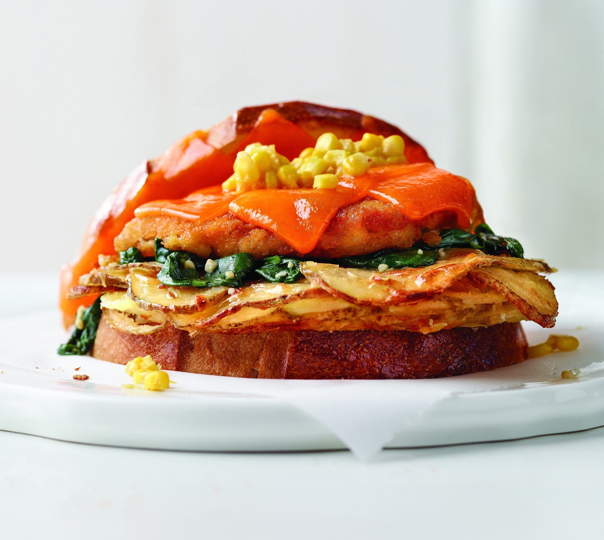 A crusty, cheesy, chicken sandwich! This chicken sandwich is topped with creamy scalloped potatoes, creamed corn puree, and garlic spinach atop perfectly fried chicken.