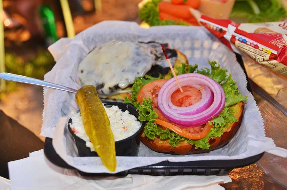 A mouth-watering burger from Fred and Fuzzy's, served with fresh onions, lettuce, tomatoes and a pickle slice.