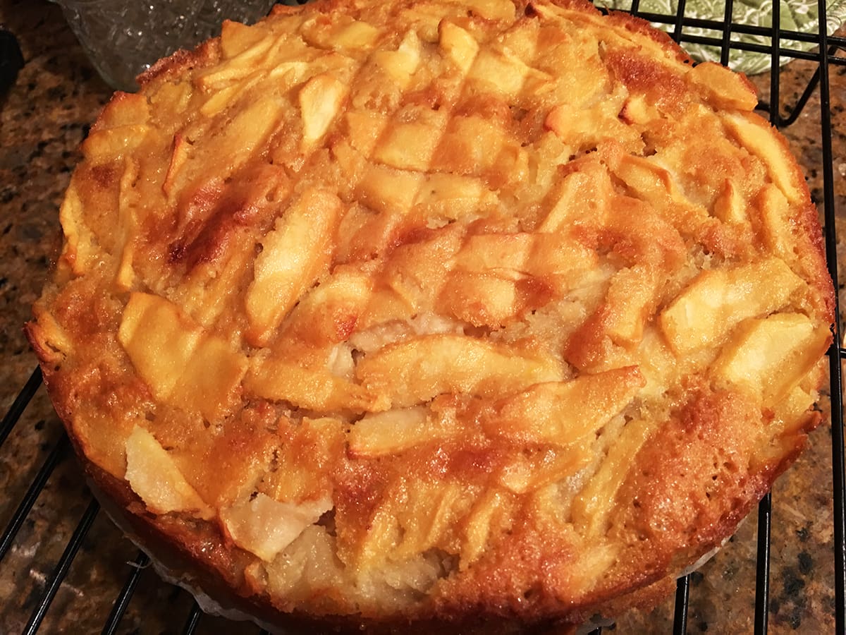 A top view of a beautiful Custard Apple cake, perfectly browned on top and made with fresh baked apple filling.