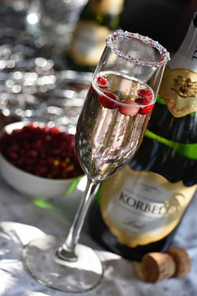 Dip the rim of a champagne flute in melted white chocolate, then dip in finely crushed candy cane. Pour crème de cacao into a champagne flute. Top with Korbel.