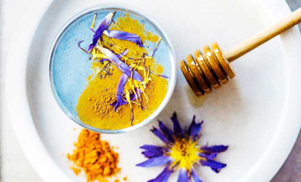 Honey dipper on a plate with spices and edible flowers.