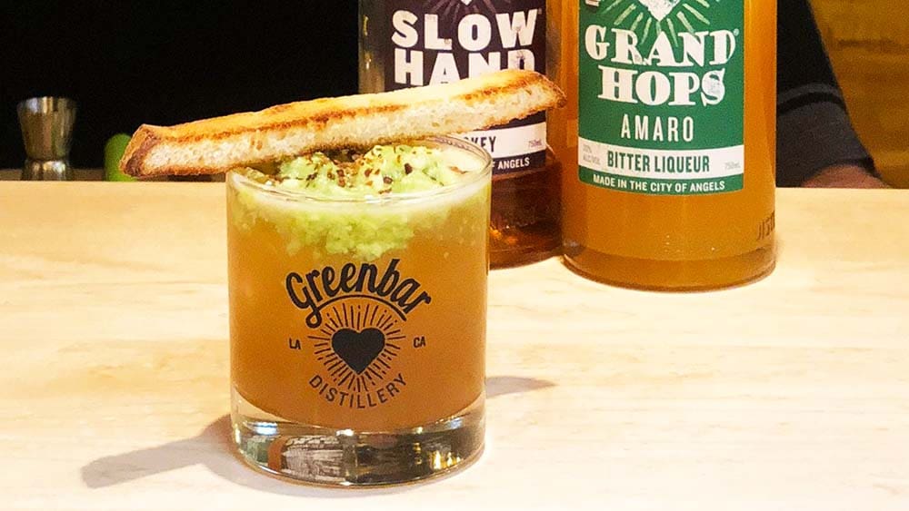 An avocado toast cocktail made with whiskey, demaro, lemon juice, infused toast, avocado, chili flakes and sea salt.